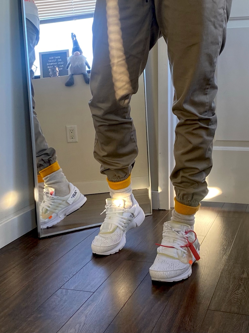 ホワイト系のスニーカー、ホワイト系のニット/セーター、ゴールド系のダウンベストを着用したメンズの冬コーディネートの3枚目の写真