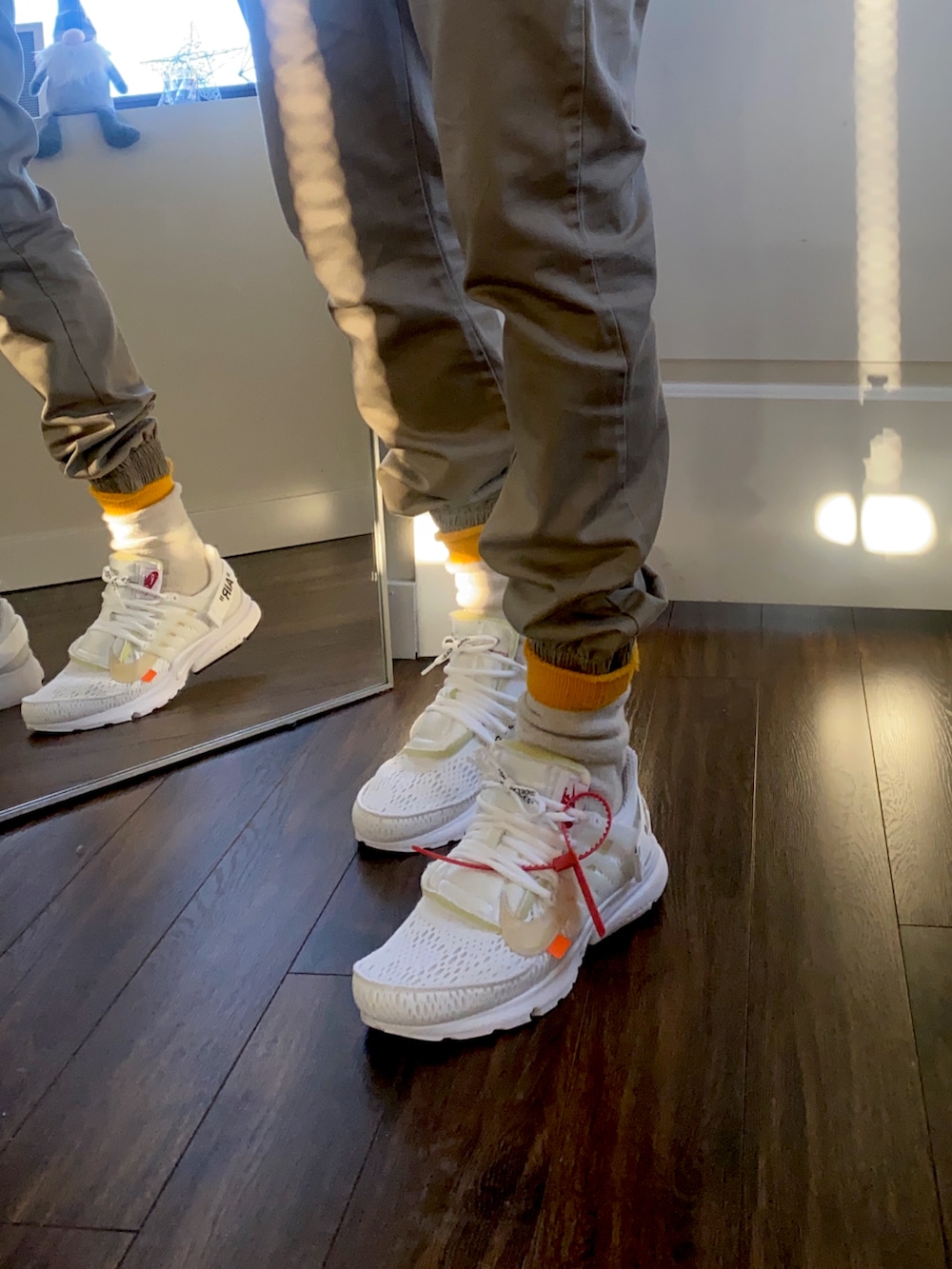 ホワイト系のスニーカー、ホワイト系のニット/セーター、ゴールド系のダウンベストを着用したメンズの冬コーディネートの5枚目の写真