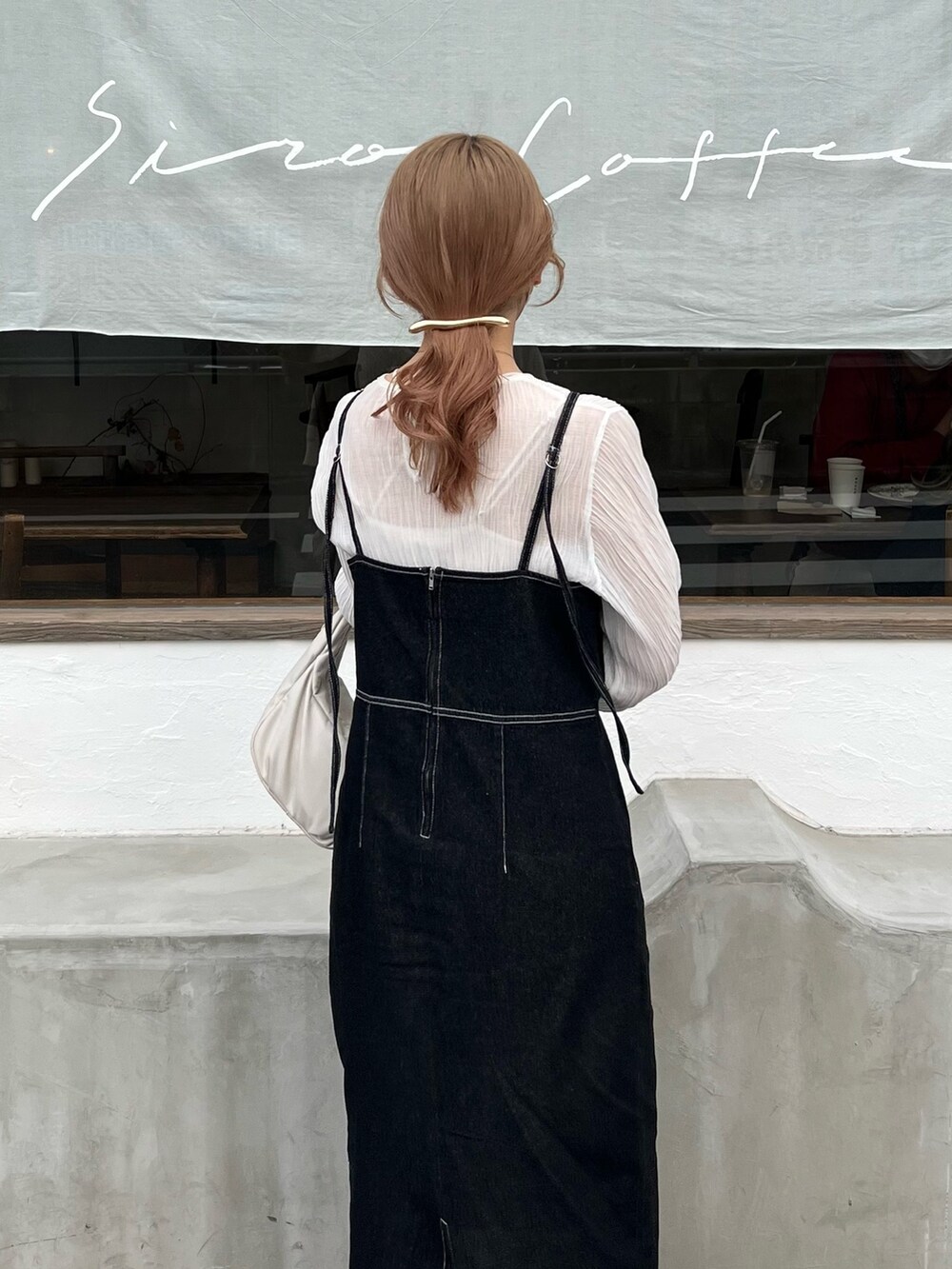 ブラウン系のスニーカー、ブラック系のワンピース、ホワイト系のハンドバッグを着用したレディースの春コーディネートの3枚目の写真