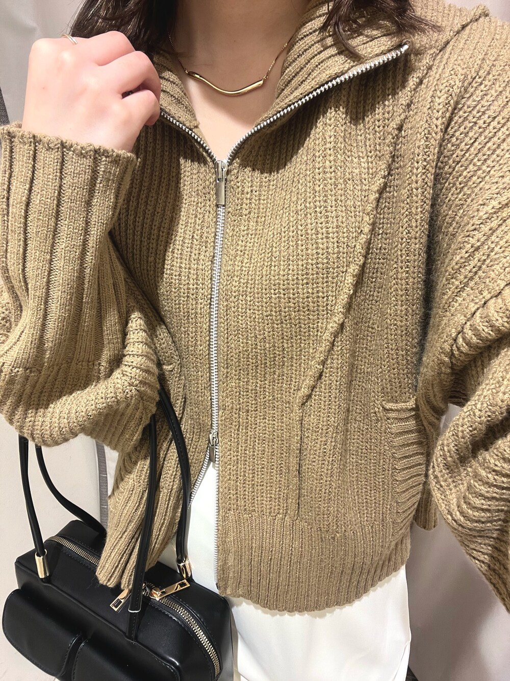 ベージュ系のカーディガン/ボレロ、ホワイト系のスカート、ブラック系のショルダーバッグを着用したレディースの冬コーディネートの2枚目の写真