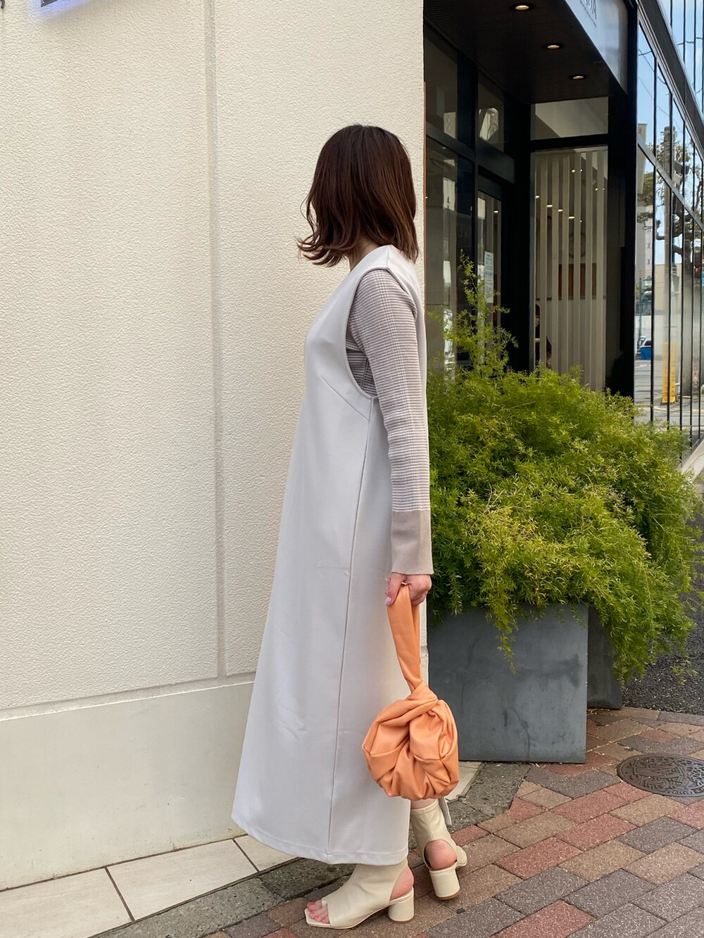 ブラック系のその他シューズ、オレンジ系のハンドバッグ、ベージュ系のニット/セーターを着用したレディースの春コーディネートの2枚目の写真