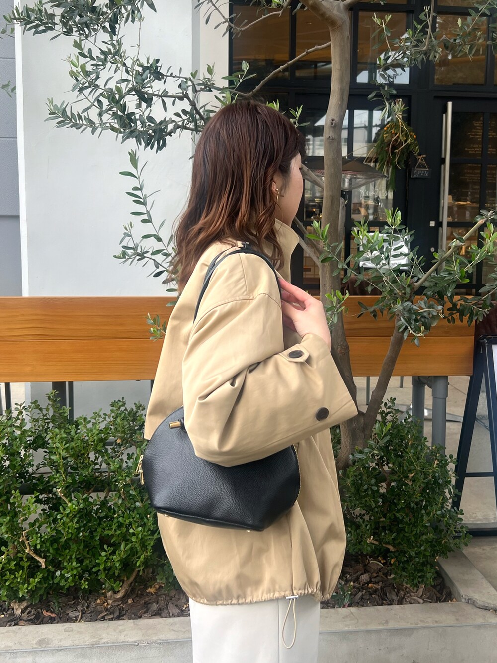 ホワイト系のスカート、ベージュ系のその他アウター、ブラック系のショルダーバッグを着用したレディースの冬コーディネートの2枚目の写真