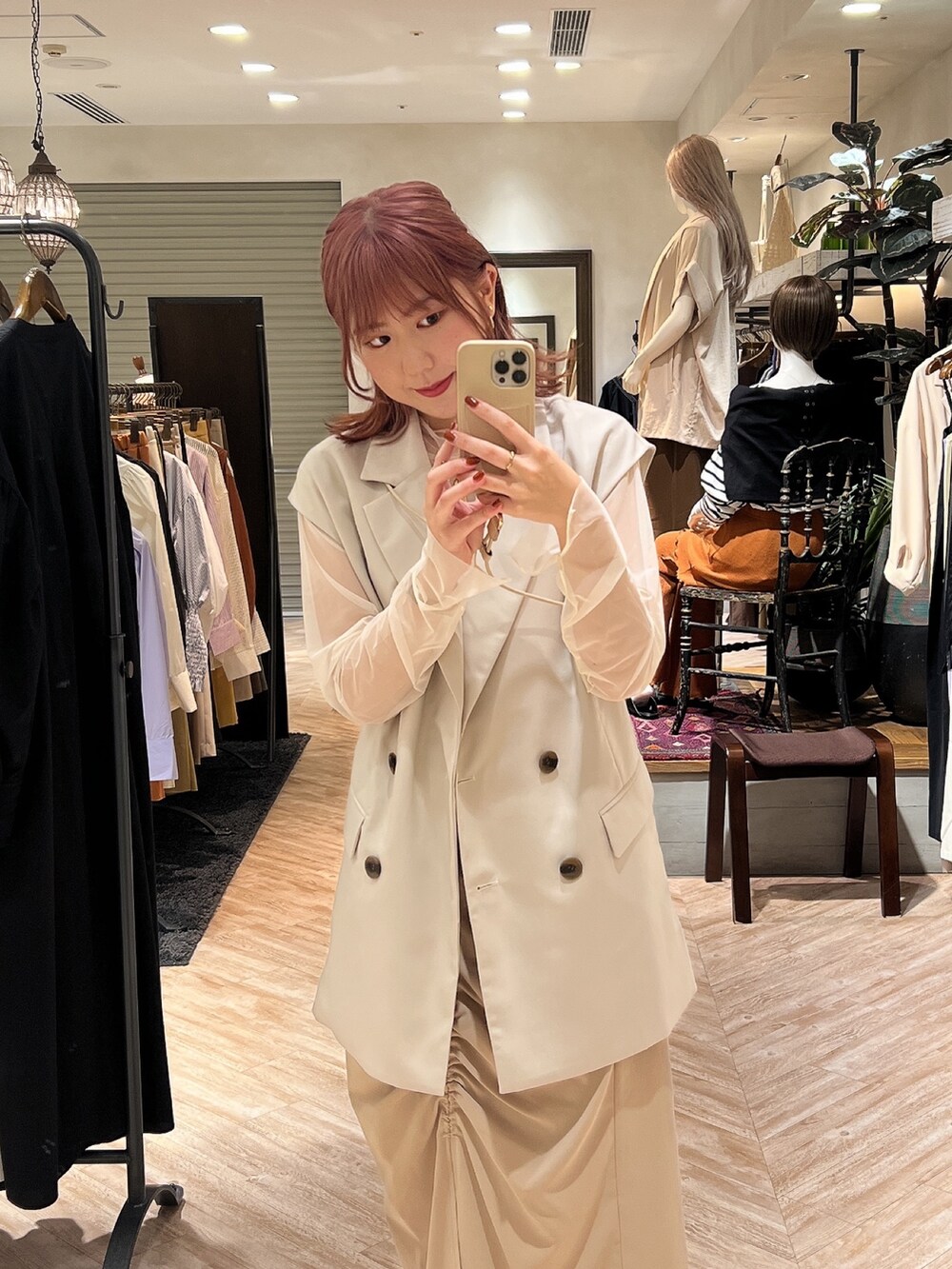 ホワイト系のブーツ、ベージュ系のスカート、ホワイト系のベストを着用したレディースの秋コーディネートの3枚目の写真