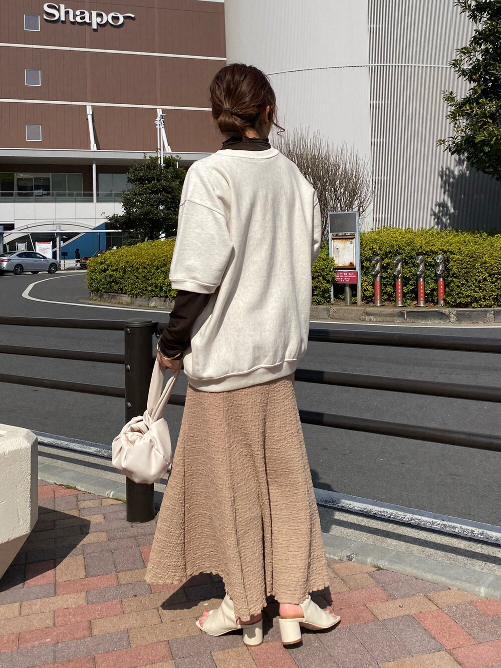 ブラック系のその他シューズ、ベージュ系のスカート、オレンジ系のハンドバッグを着用したレディースの春コーディネートの2枚目の写真