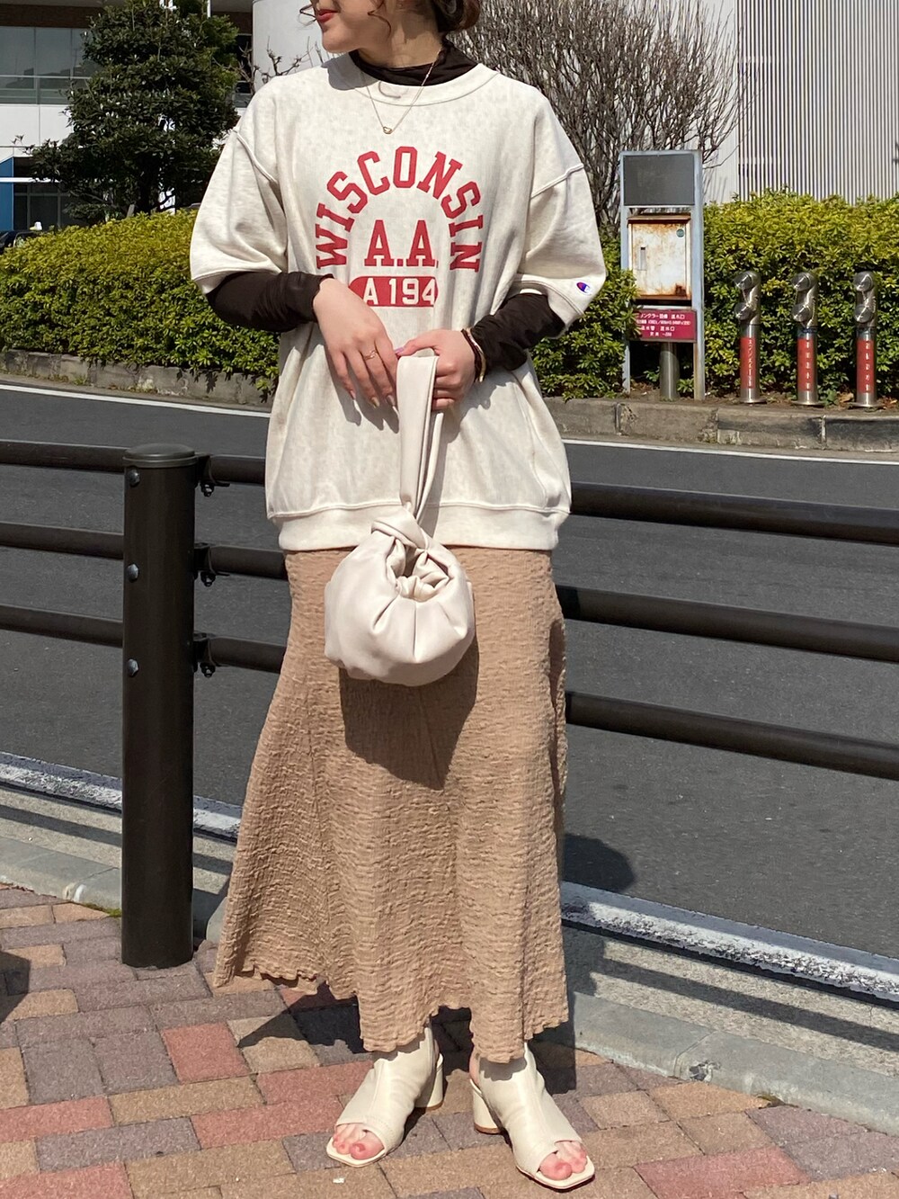 ブラック系のその他シューズ、ベージュ系のスカート、オレンジ系のハンドバッグを着用したレディースの春コーディネートの3枚目の写真