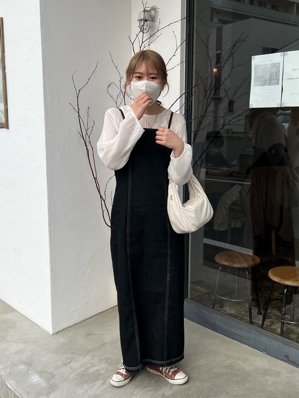 ブラウン系のスニーカー、ブラック系のワンピース、ホワイト系のハンドバッグを着用したレディースの春コーディネートの2枚目の写真