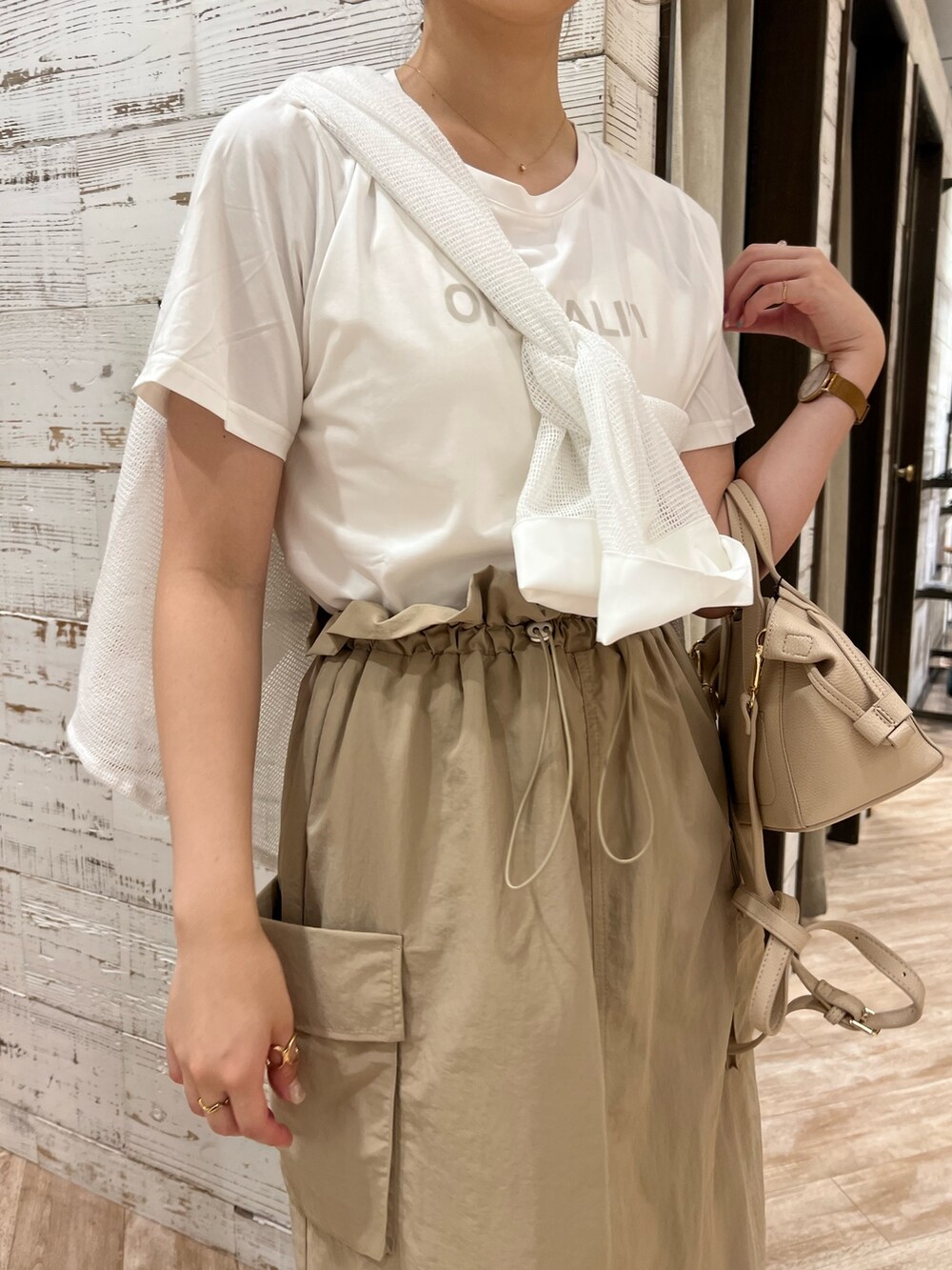 ベージュ系のスカート、ホワイト系のTシャツ/カットソー、ベージュ系のハンドバッグを着用したレディースの夏コーディネートの2枚目の写真