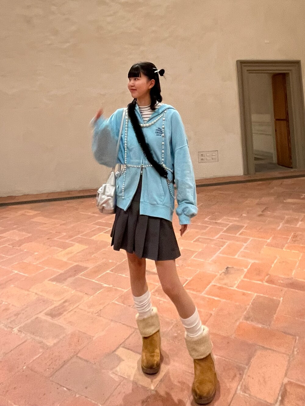 ブルー系のパーカー、シルバー系のショルダーバッグ、グレー系のスカートを着用したレディースの春コーディネートの2枚目の写真