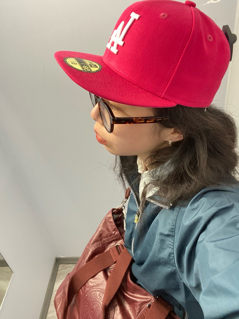 ブルー系のナイロンジャケット、レッド系のバッグ、ピンク系の帽子を着用したレディースの春コーディネートの3枚目の写真