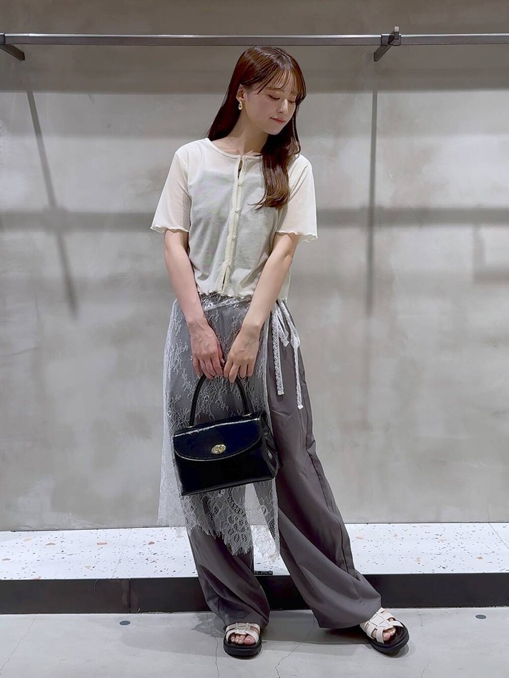 ホワイト系のサンダル、グレー系のその他パンツ、ブラック系のボストンバッグを着用したレディースの夏コーディネートの2枚目の写真