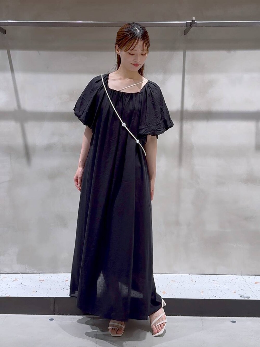 ベージュ系のキャミソール、ホワイト系のサンダル、ブラック系のワンピースを着用したレディースの夏コーディネートの2枚目の写真