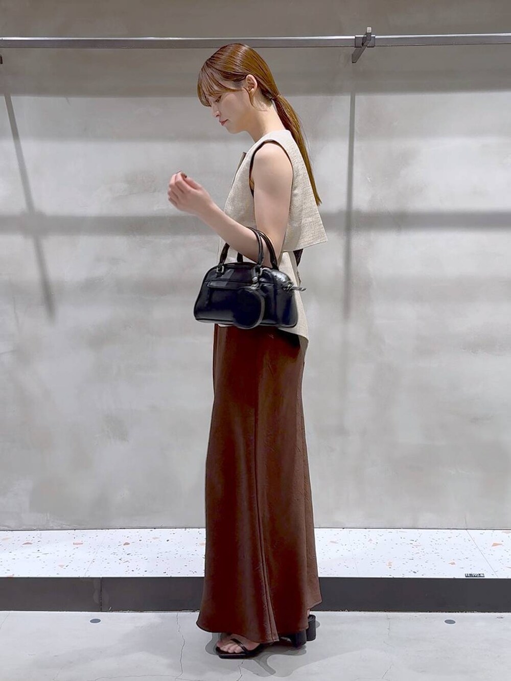 ブラウン系のスカート、ベージュ系のブルゾン、ブラック系のサンダルを着用したレディースの夏コーディネートの4枚目の写真