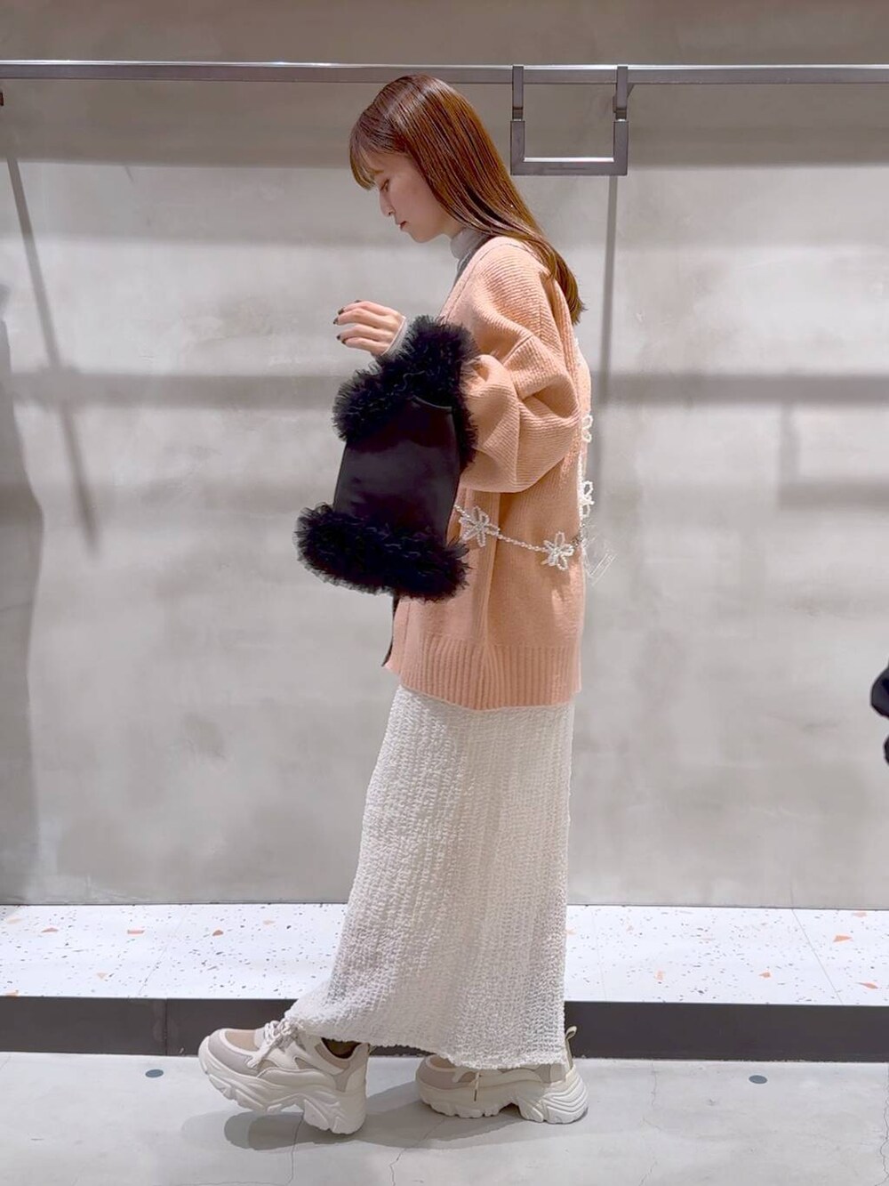 ベージュ系のTシャツ/カットソー、ホワイト系のスカート、ベージュ系のスニーカーを着用したレディースの冬コーディネートの4枚目の写真