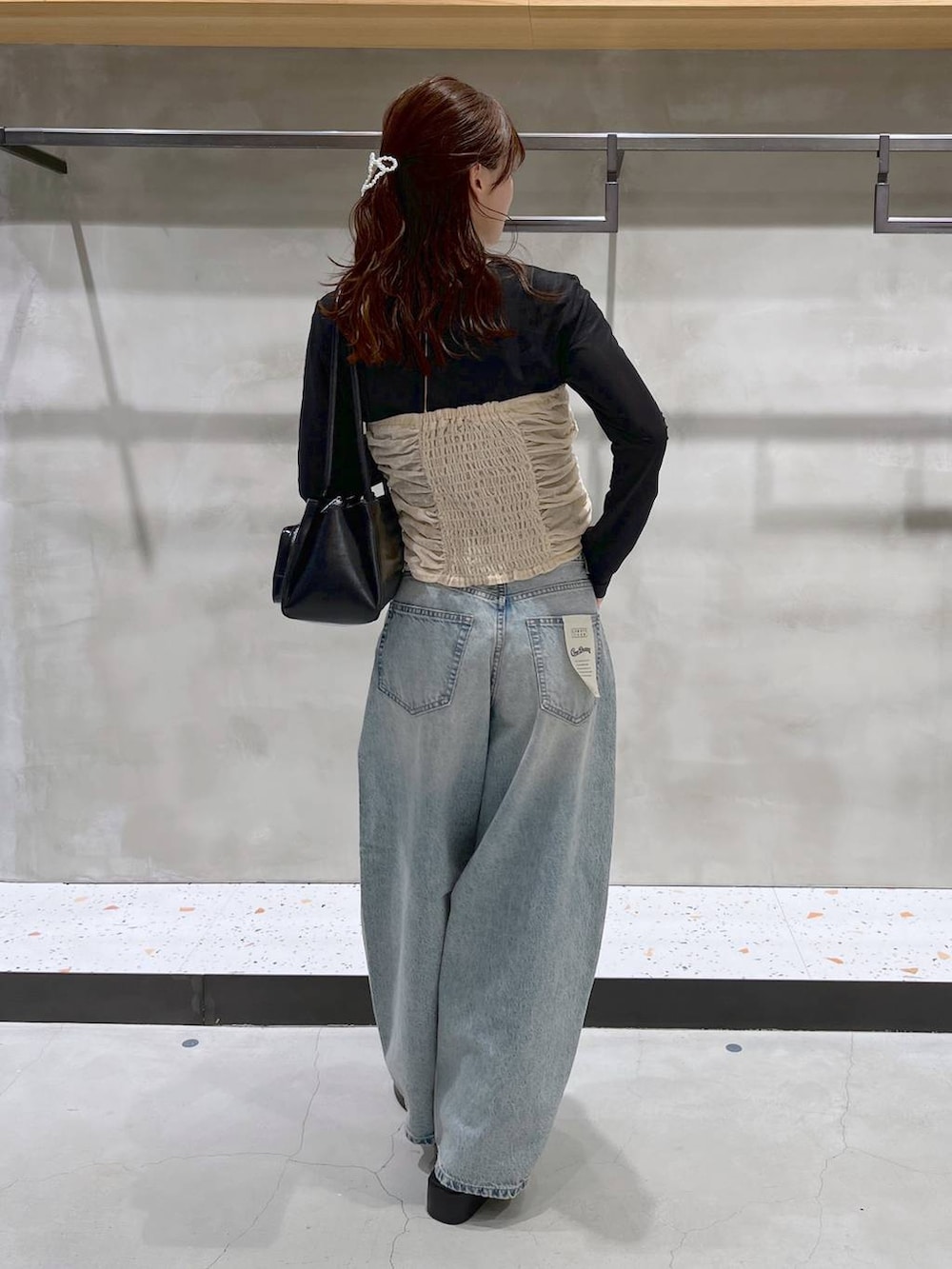 ブルー系のデニムパンツ、ブラック系のサンダル、ブラック系のショルダーバッグを着用したレディースの夏コーディネートの4枚目の写真