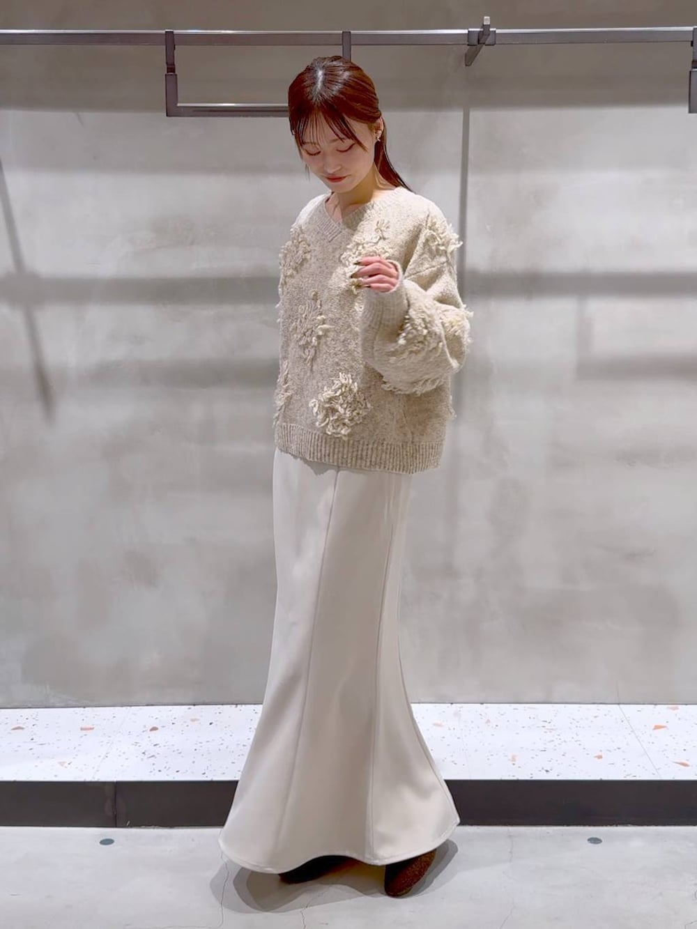 ブラウン系のバレエシューズ、ベージュ系のスカート、ベージュ系のニット/セーターを着用したレディースの冬コーディネートの2枚目の写真