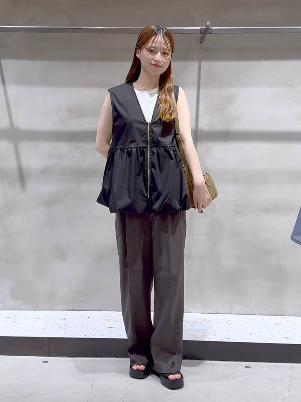 ブラック系のサンダル、ホワイト系のキャミソール、グレー系のスラックスを着用したレディースの夏コーディネートの2枚目の写真