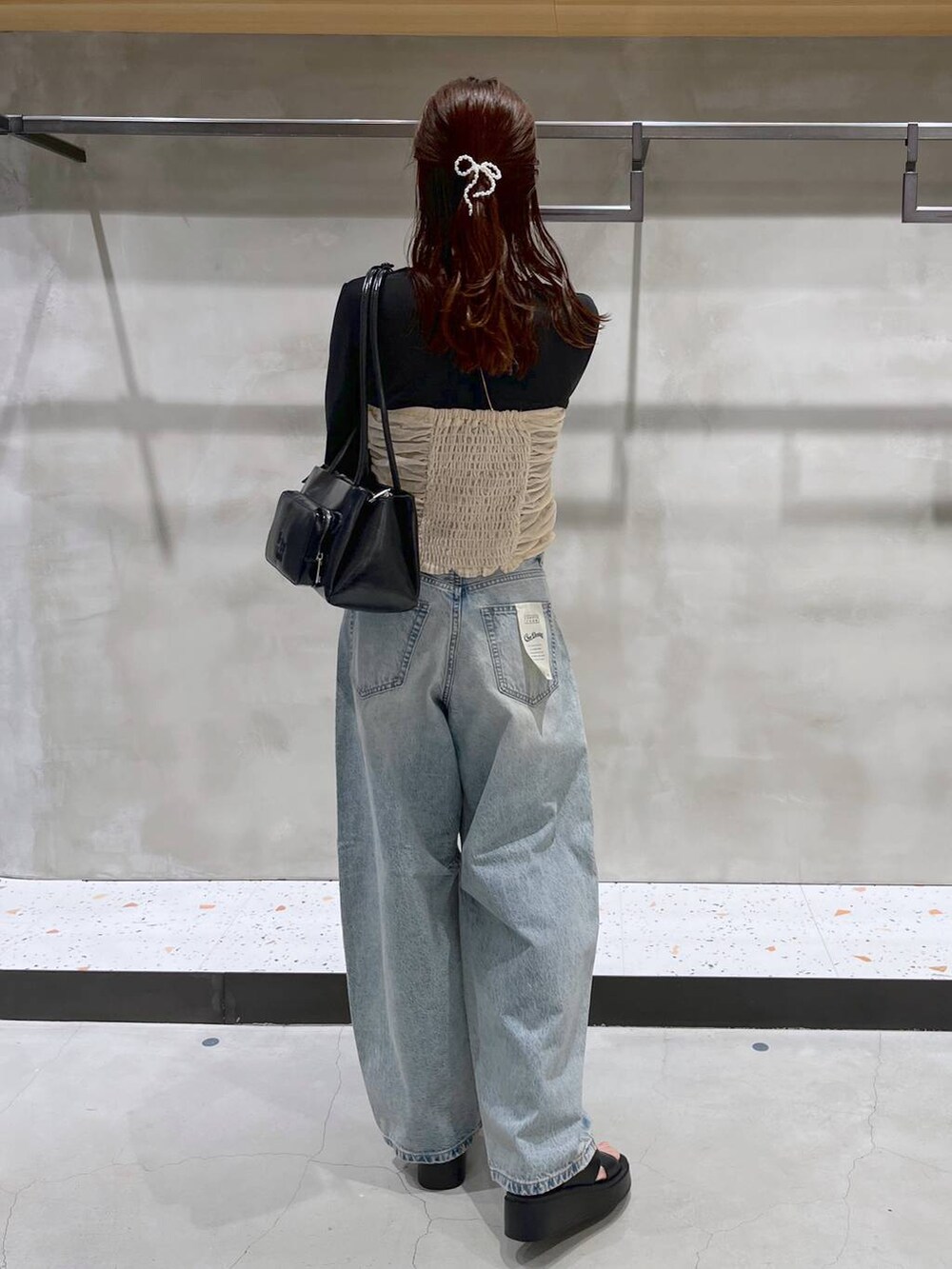 ブルー系のデニムパンツ、ブラック系のサンダル、ブラック系のショルダーバッグを着用したレディースの夏コーディネートの3枚目の写真