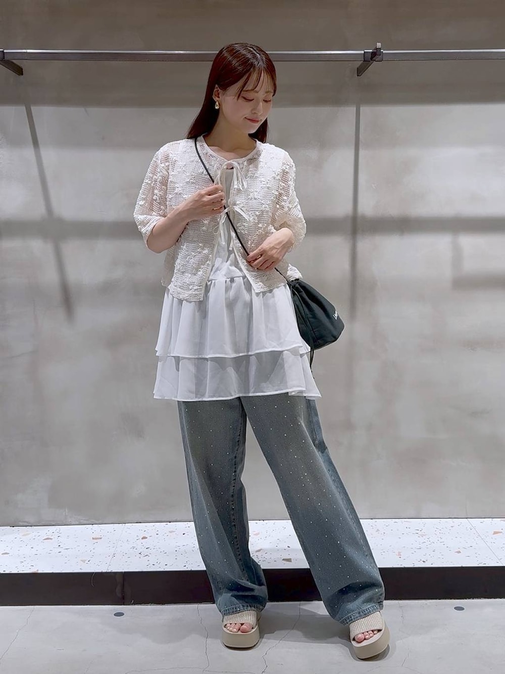 ブルー系のデニムパンツ、ホワイト系のサンダル、ホワイト系のタンクトップを着用したレディースの夏コーディネートの2枚目の写真