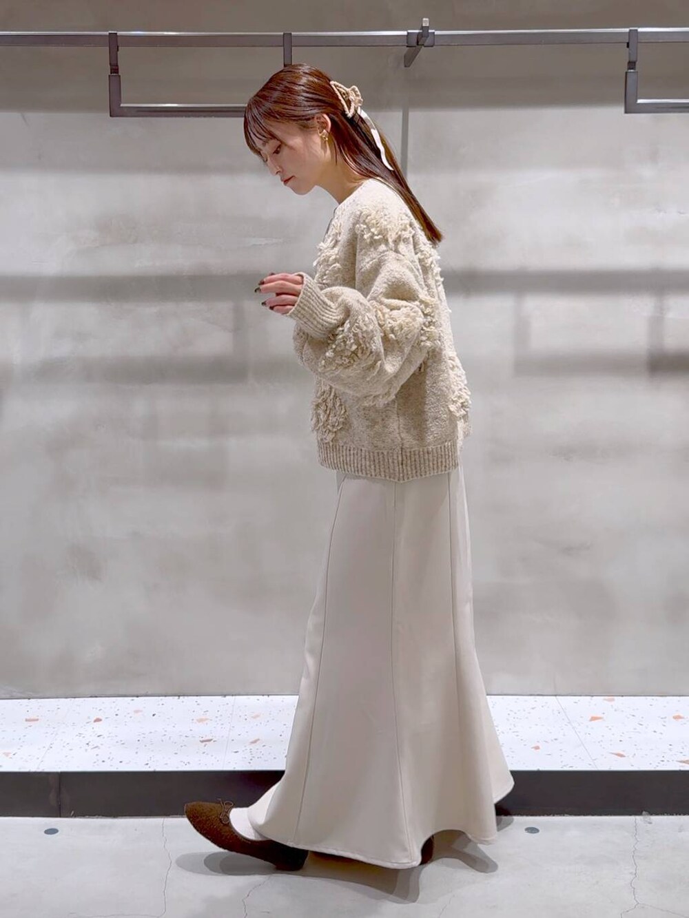 ブラウン系のバレエシューズ、ベージュ系のスカート、ベージュ系のニット/セーターを着用したレディースの冬コーディネートの3枚目の写真