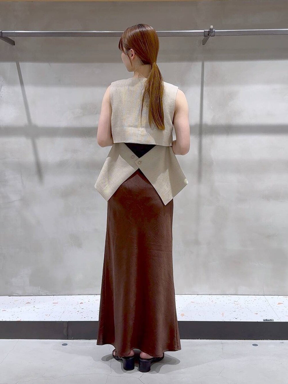 ブラウン系のスカート、ベージュ系のブルゾン、ブラック系のサンダルを着用したレディースの夏コーディネートの5枚目の写真