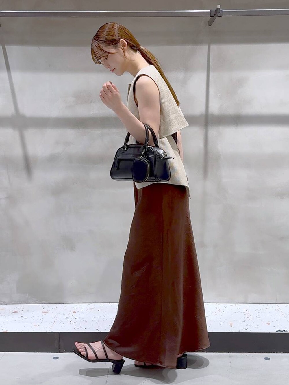 ブラウン系のスカート、ベージュ系のブルゾン、ブラック系のサンダルを着用したレディースの夏コーディネートの3枚目の写真