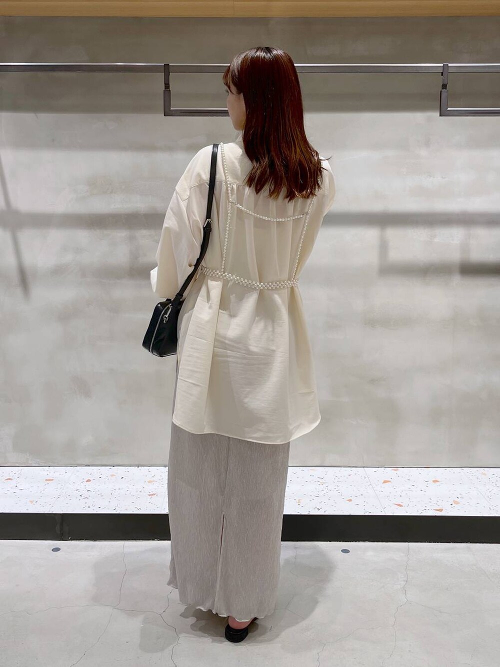 ブラック系のパンプス、ホワイト系のスカート、ブラック系のボストンバッグを着用したレディースの秋コーディネートの6枚目の写真