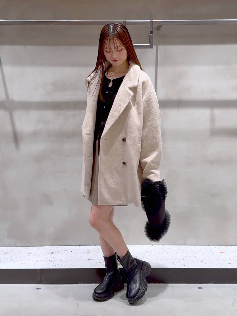 ブラック系のブーツ、ブラック系のトートバッグ、ベージュ系のその他アウターを着用したレディースの冬コーディネートの6枚目の写真