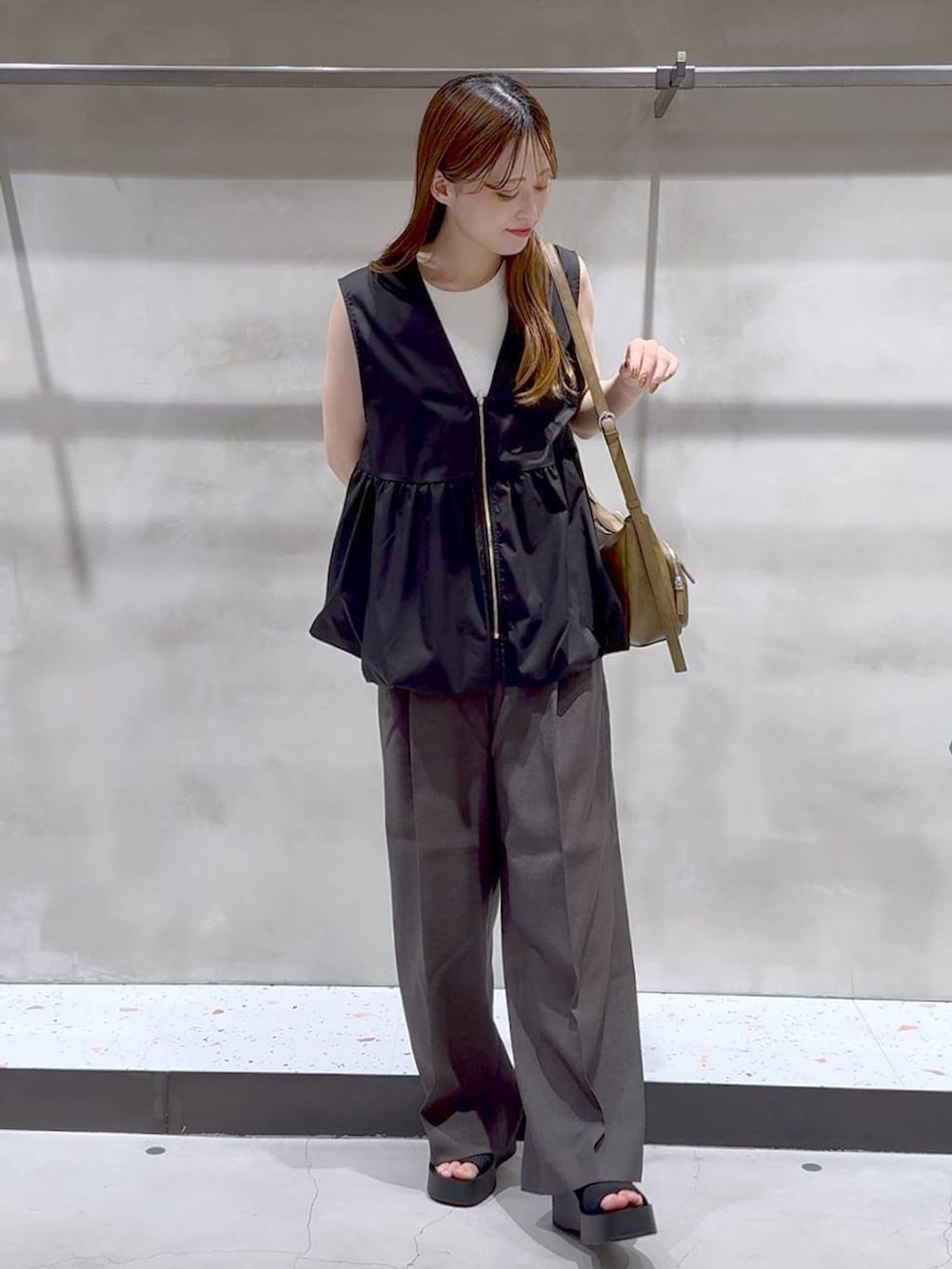 ブラック系のサンダル、ホワイト系のキャミソール、グレー系のスラックスを着用したレディースの夏コーディネートの3枚目の写真