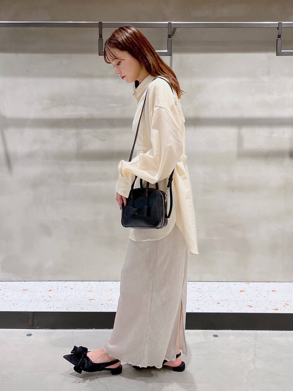 ブラック系のパンプス、ホワイト系のスカート、ブラック系のボストンバッグを着用したレディースの秋コーディネートの5枚目の写真