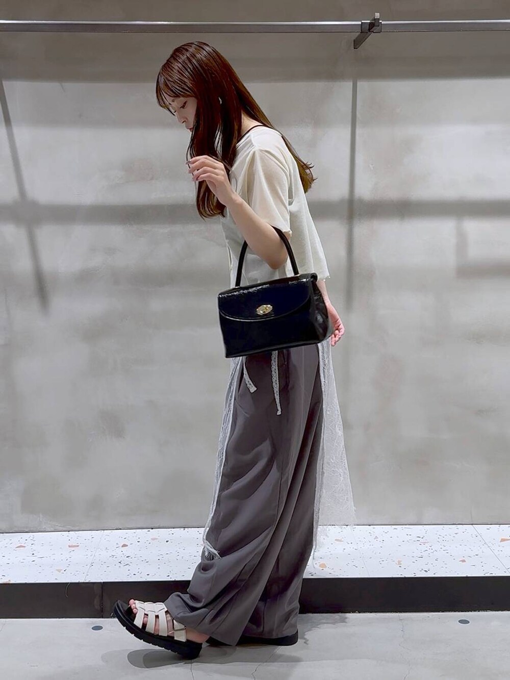 ホワイト系のサンダル、グレー系のその他パンツ、ブラック系のボストンバッグを着用したレディースの夏コーディネートの3枚目の写真