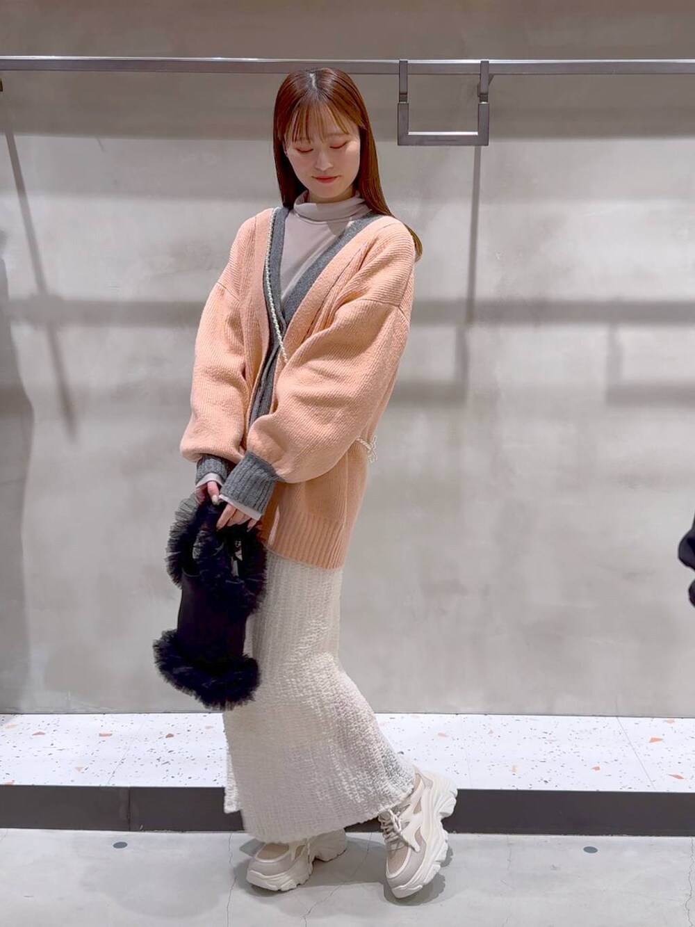 ベージュ系のTシャツ/カットソー、ホワイト系のスカート、ベージュ系のスニーカーを着用したレディースの冬コーディネートの3枚目の写真