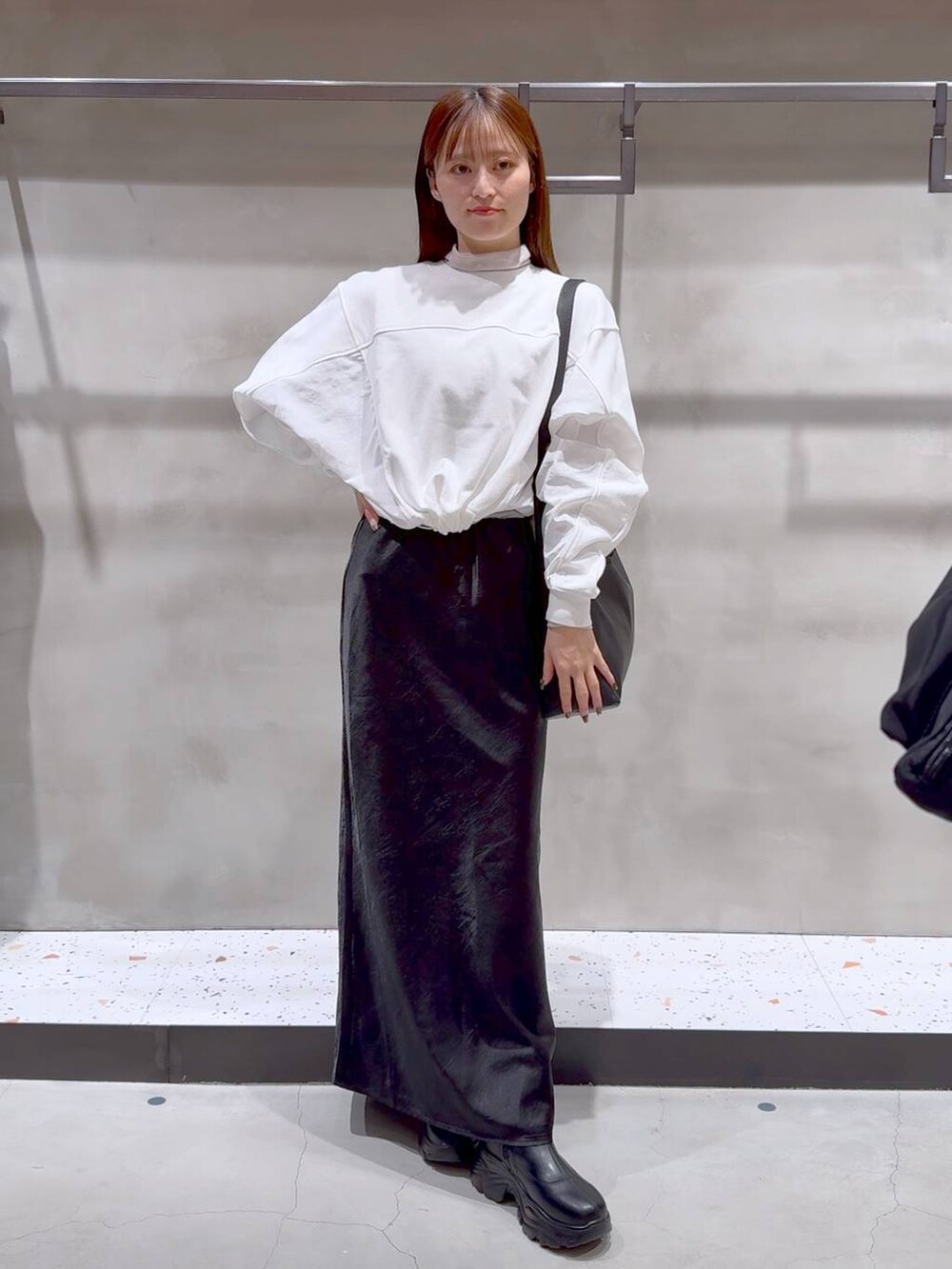 ブラック系のショルダーバッグ、ブラック系のブーツ、ブラック系のスカートを着用したレディースの冬コーディネートの2枚目の写真