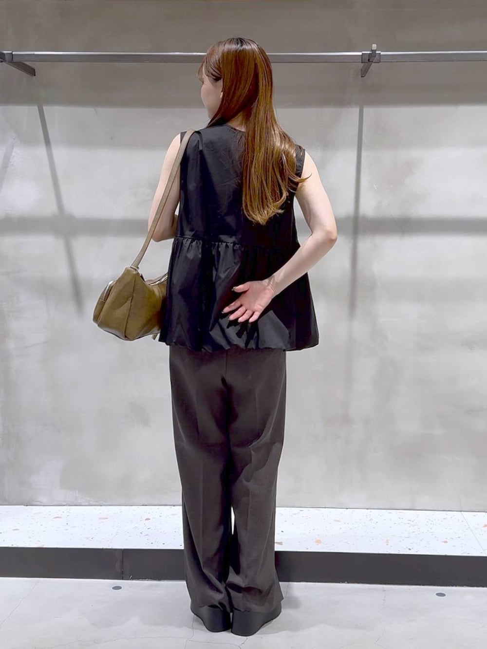 ブラック系のサンダル、ホワイト系のキャミソール、グレー系のスラックスを着用したレディースの夏コーディネートの5枚目の写真