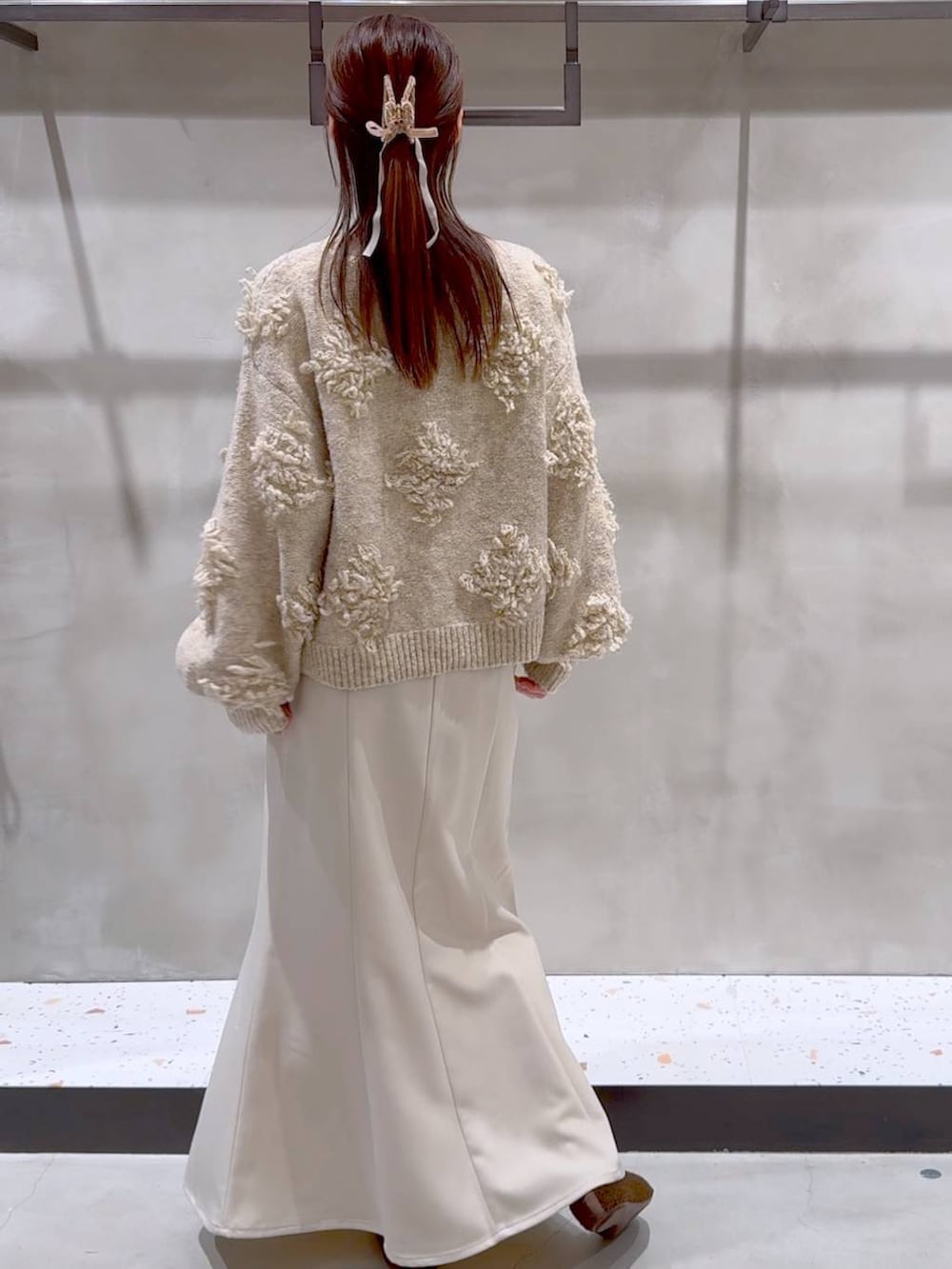 ブラウン系のバレエシューズ、ベージュ系のスカート、ベージュ系のニット/セーターを着用したレディースの冬コーディネートの5枚目の写真