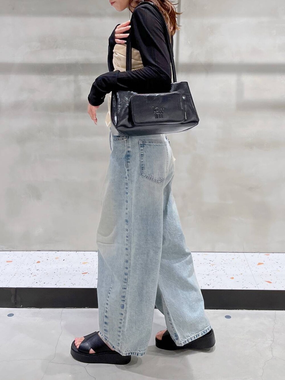 ブルー系のデニムパンツ、ブラック系のサンダル、ブラック系のショルダーバッグを着用したレディースの夏コーディネートの2枚目の写真