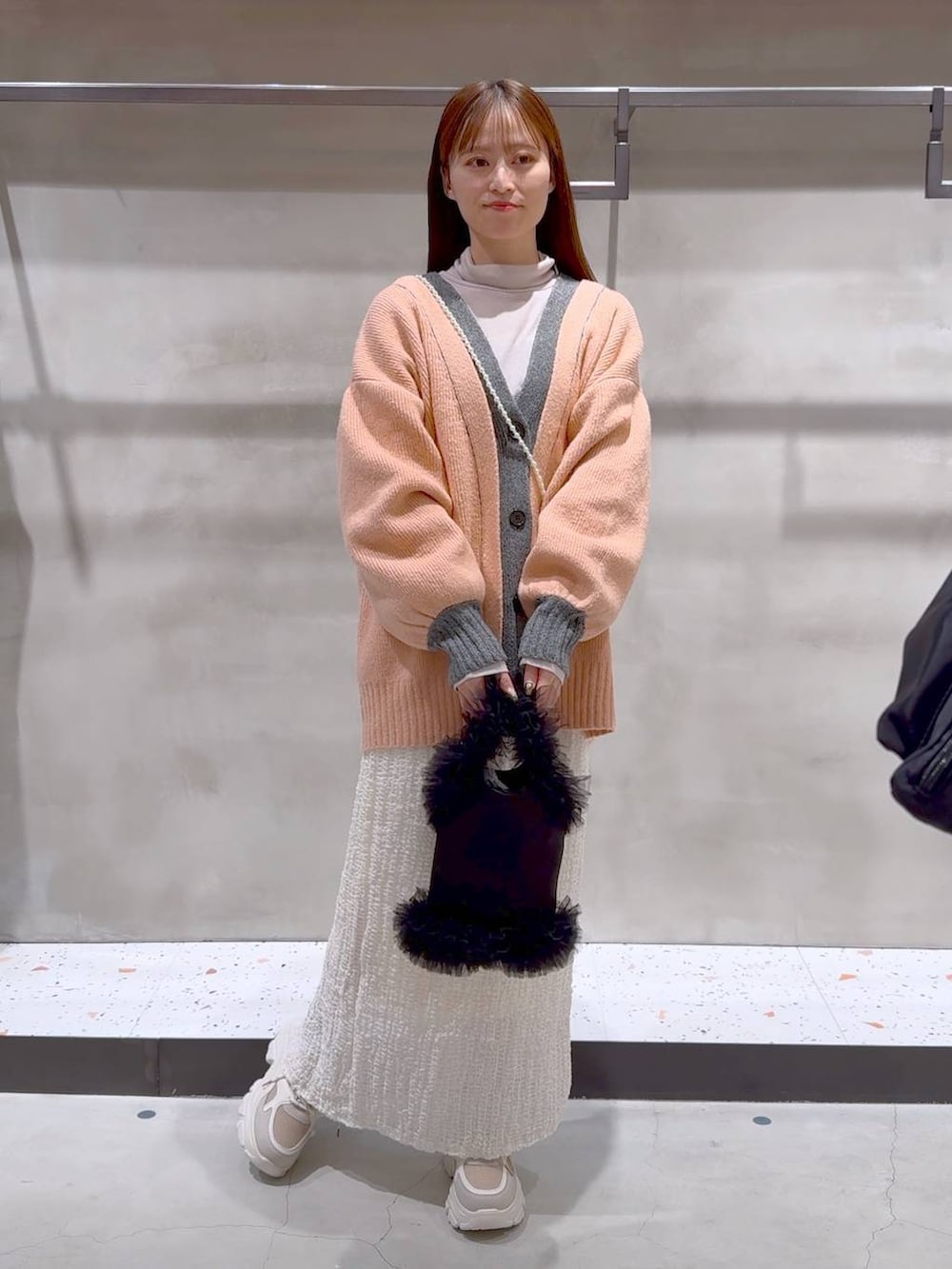 ベージュ系のTシャツ/カットソー、ホワイト系のスカート、ベージュ系のスニーカーを着用したレディースの冬コーディネートの2枚目の写真