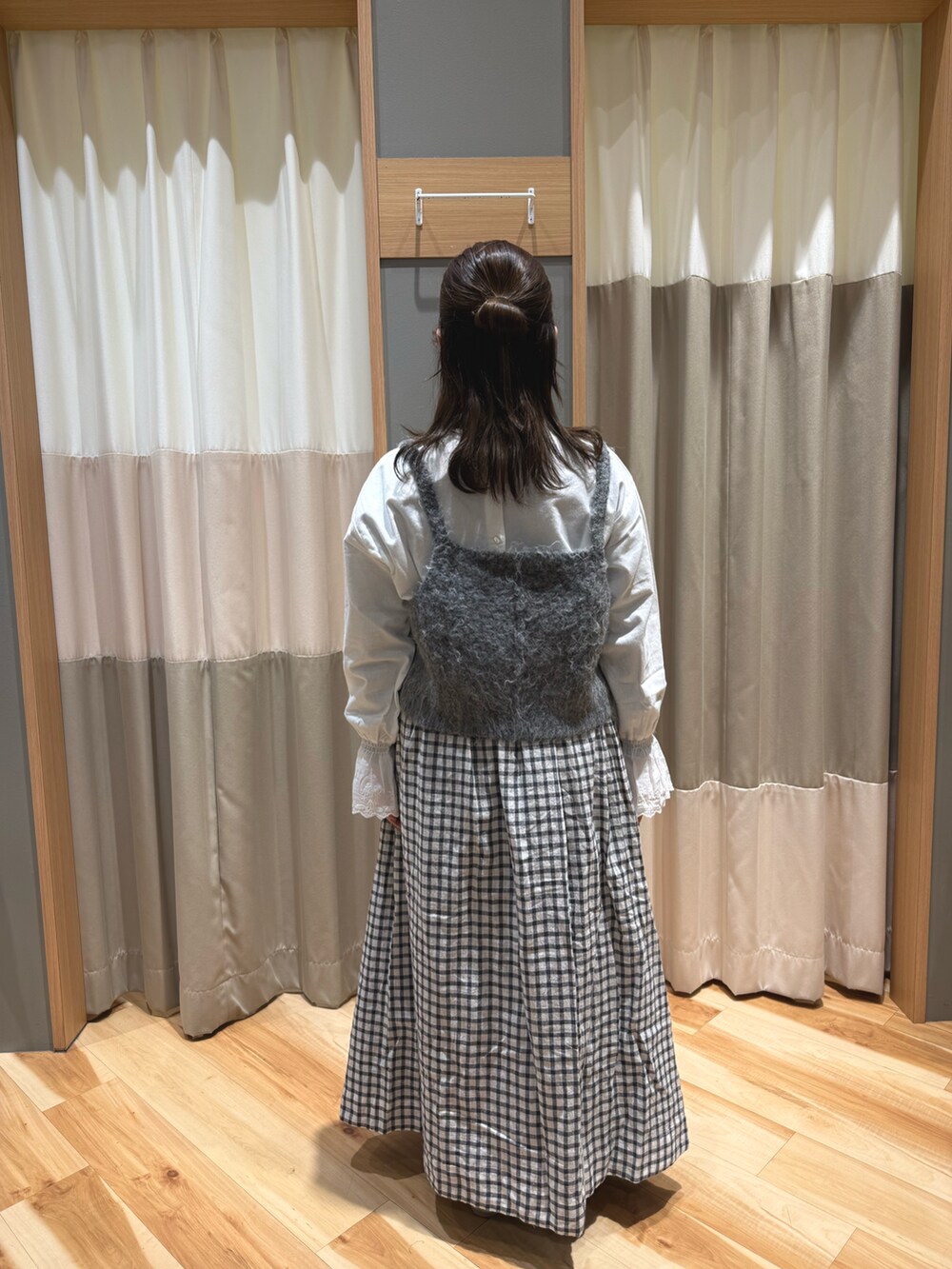 グレー系のスカート、シルバー系のパンプス、グレー系のベストを着用したレディースの冬コーディネートの3枚目の写真