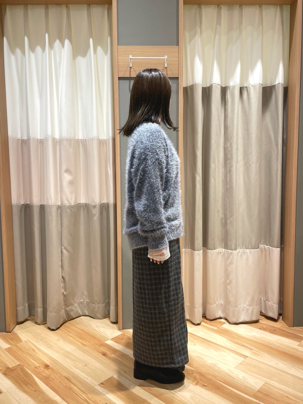 ブラック系のブーツ、グレー系のスカート、ブラック系のハンドバッグを着用したレディースの秋コーディネートの2枚目の写真