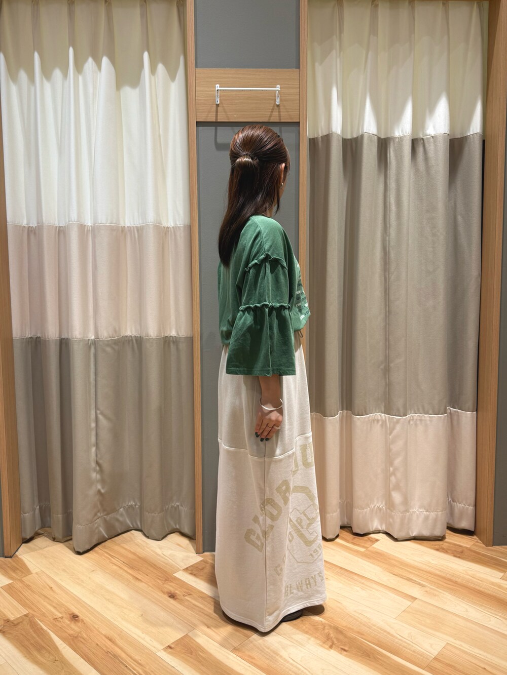 ベージュ系のスカート、グリーン系のTシャツ/カットソーを着用したレディースの春コーディネートの2枚目の写真