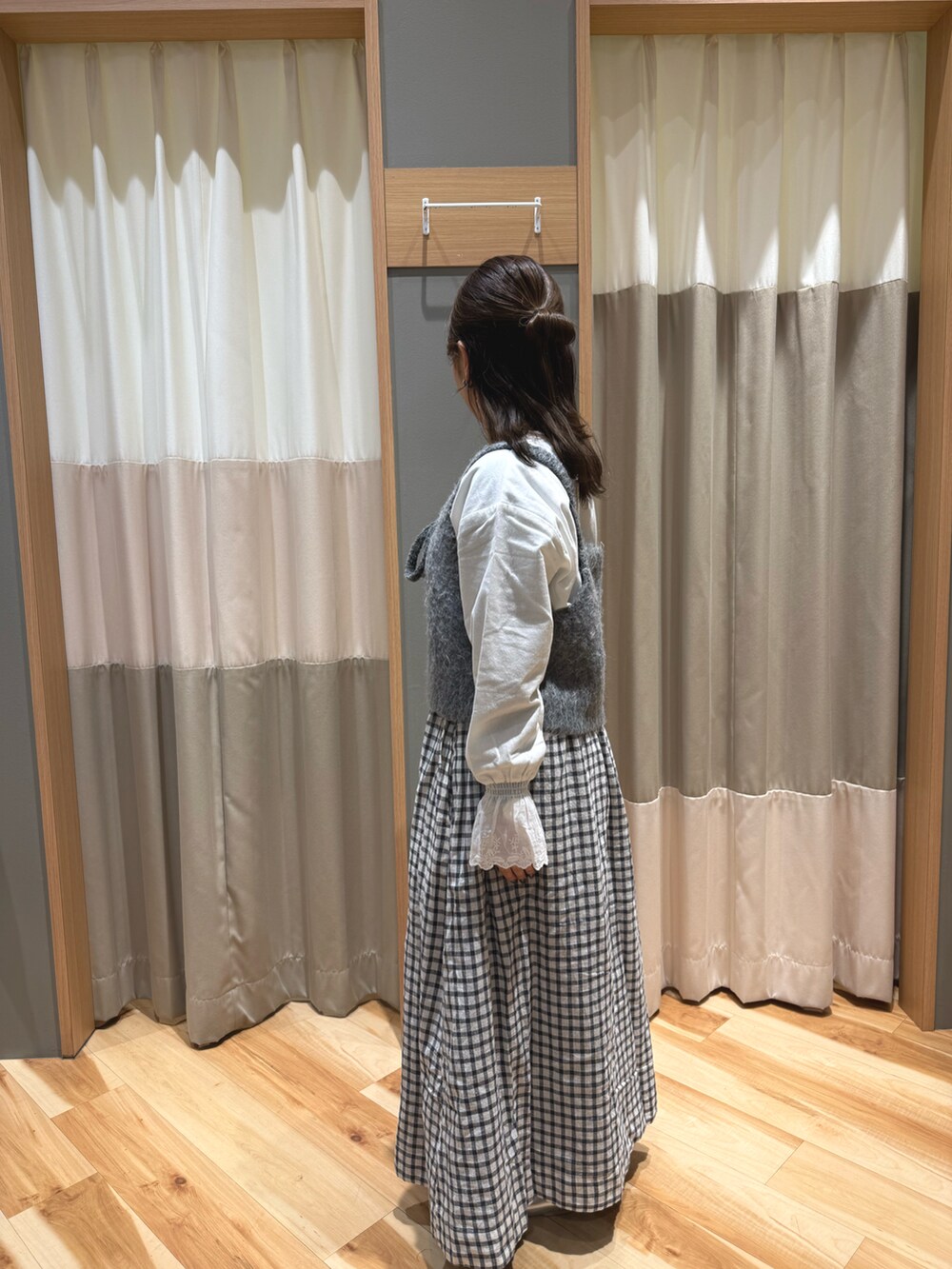 グレー系のスカート、シルバー系のパンプス、グレー系のベストを着用したレディースの冬コーディネートの4枚目の写真