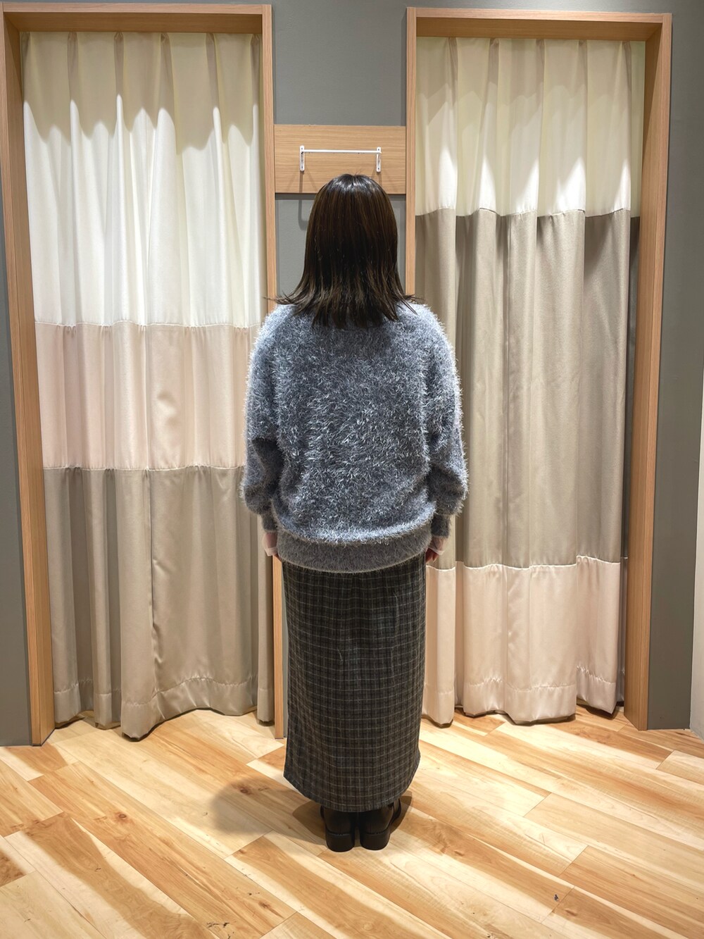 ブラック系のブーツ、グレー系のスカート、ブラック系のハンドバッグを着用したレディースの秋コーディネートの3枚目の写真