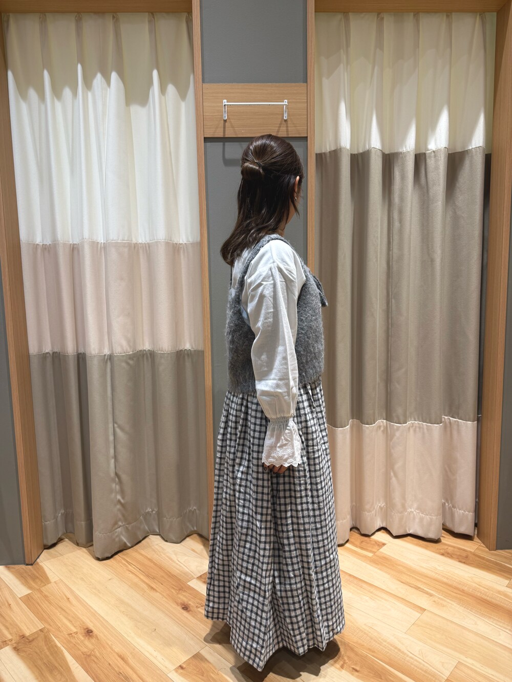 グレー系のスカート、シルバー系のパンプス、グレー系のベストを着用したレディースの冬コーディネートの2枚目の写真