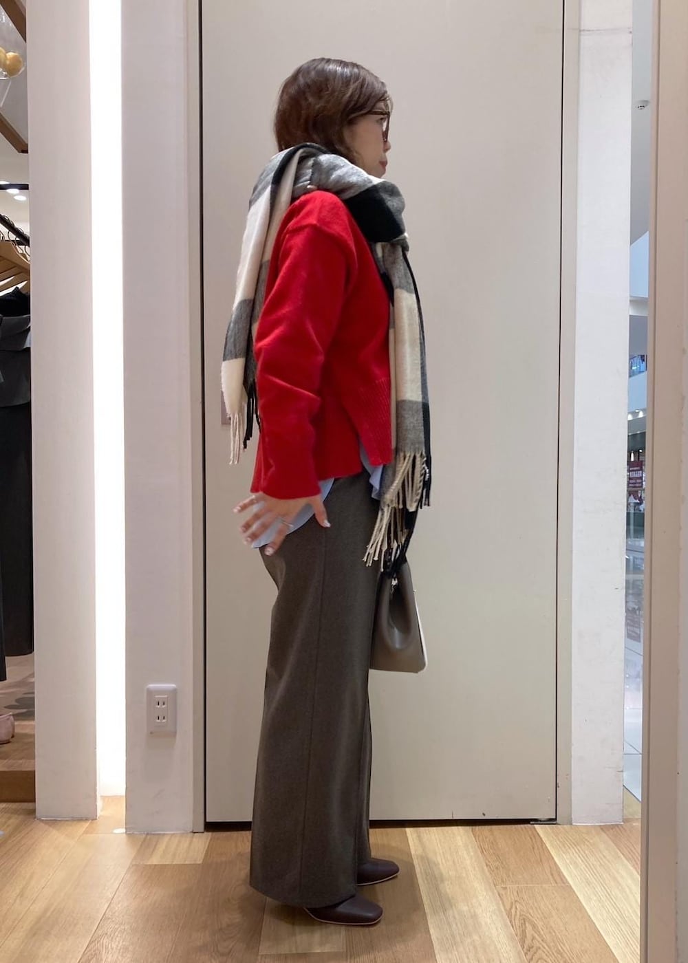 レッド系のニット/セーター、レッド系のブーツ、グレー系のトートバッグを着用したレディースの秋コーディネートの2枚目の写真