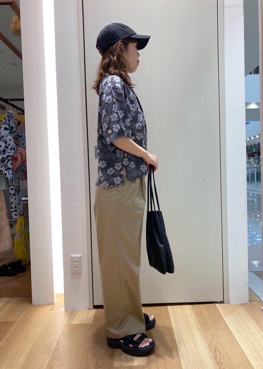 ブラック系のトートバッグ、ブラック系のサンダル、グレー系のチノパンツを着用したレディースの夏コーディネートの3枚目の写真