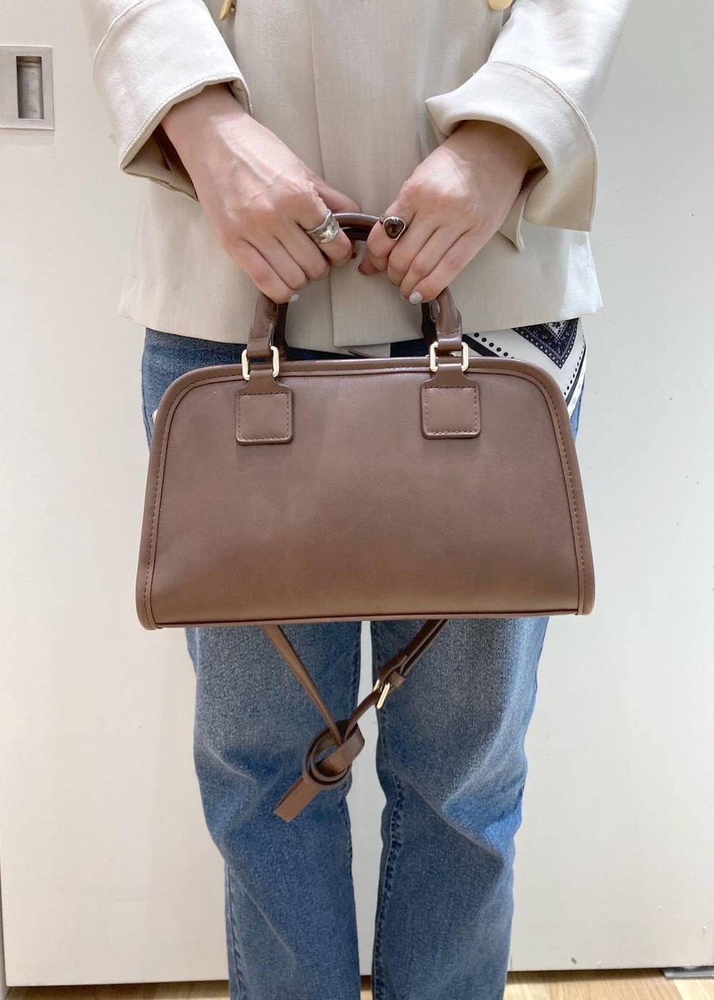 ブラウン系のボストンバッグ、ブルー系のデニムパンツ、ブラウン系のパンプスを着用したレディースの春コーディネートの10枚目の写真