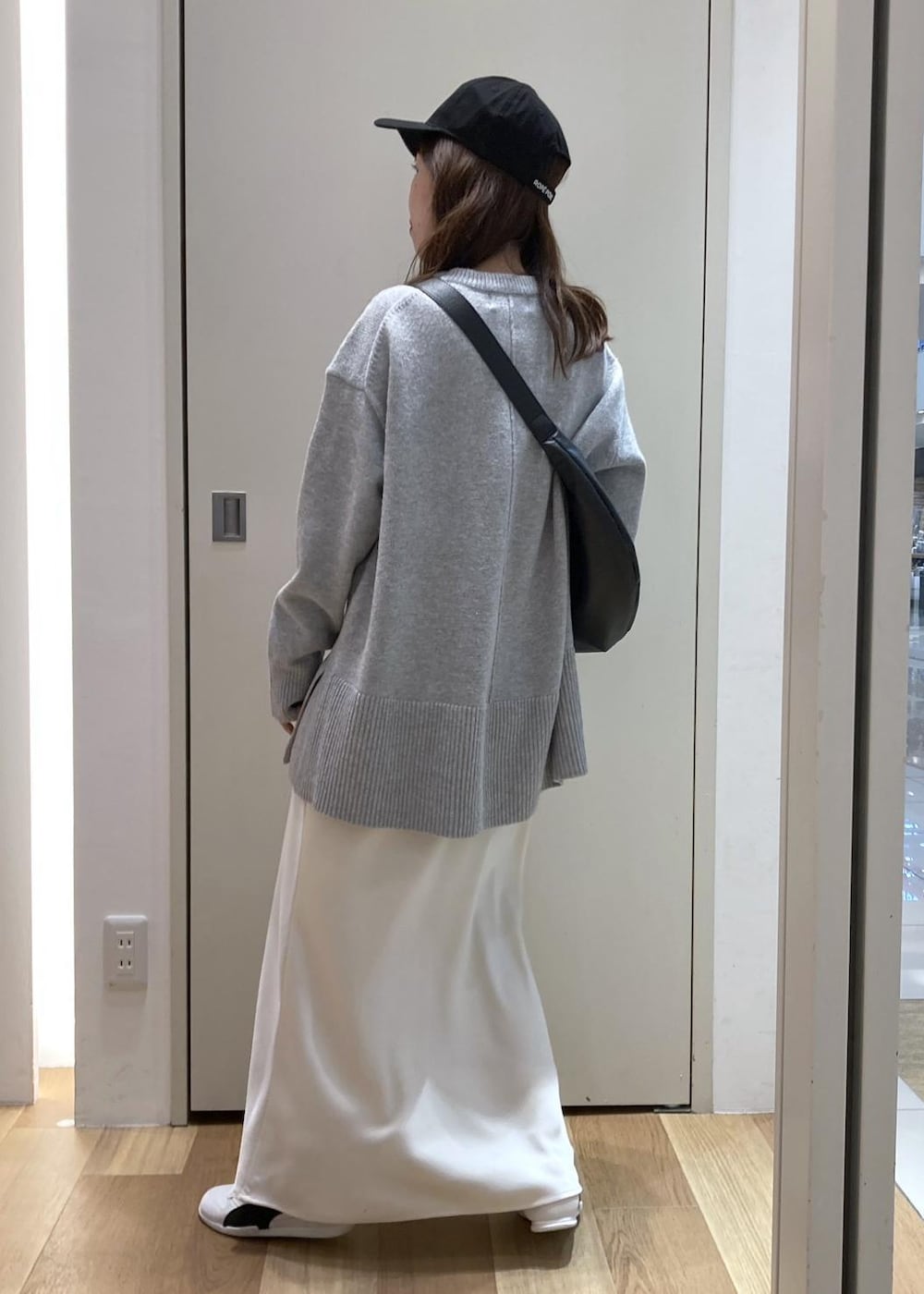 グレー系のニット/セーター、ホワイト系のスニーカー、ブラック系のショルダーバッグを着用したレディースの冬コーディネートの3枚目の写真