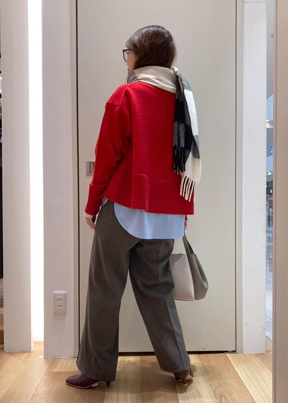 レッド系のニット/セーター、レッド系のブーツ、グレー系のトートバッグを着用したレディースの秋コーディネートの3枚目の写真