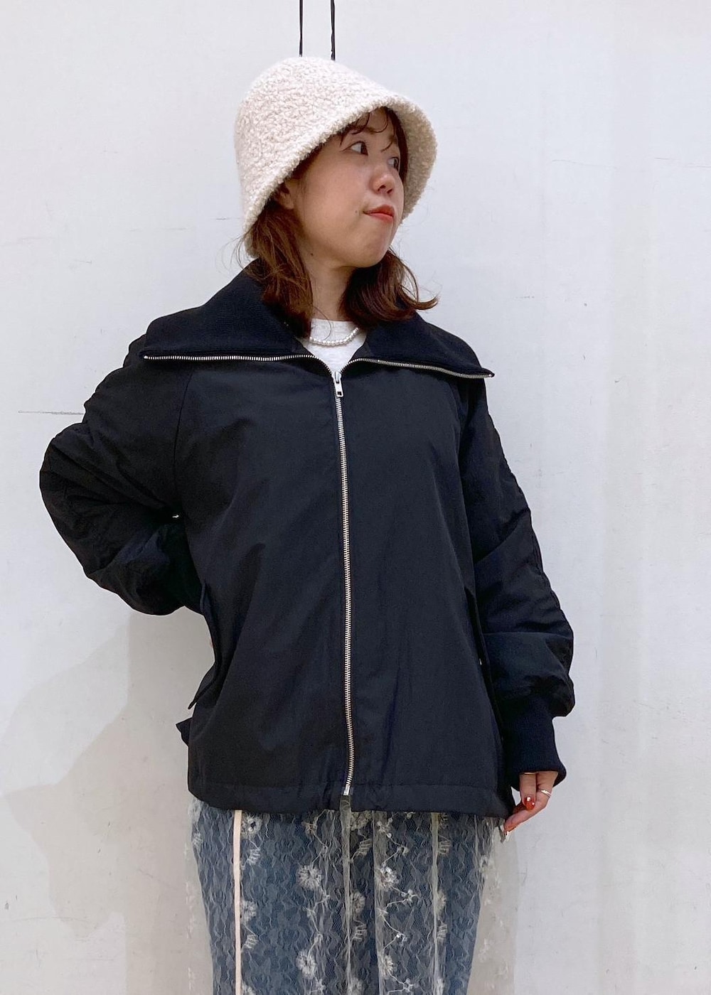 ブルー系のデニムパンツ、ホワイト系のスカート、ゴールド系のショルダーバッグを着用したレディースの秋コーディネートの4枚目の写真