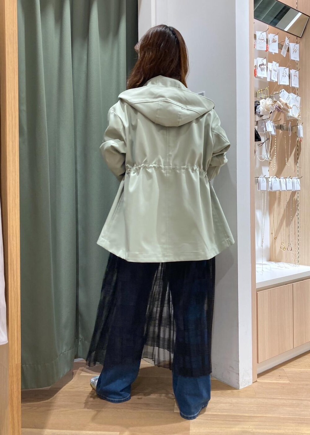 ブルー系のデニムパンツ、ブラック系のスカート、グリーン系のマウンテンパーカーを着用したレディースの春コーディネートの5枚目の写真