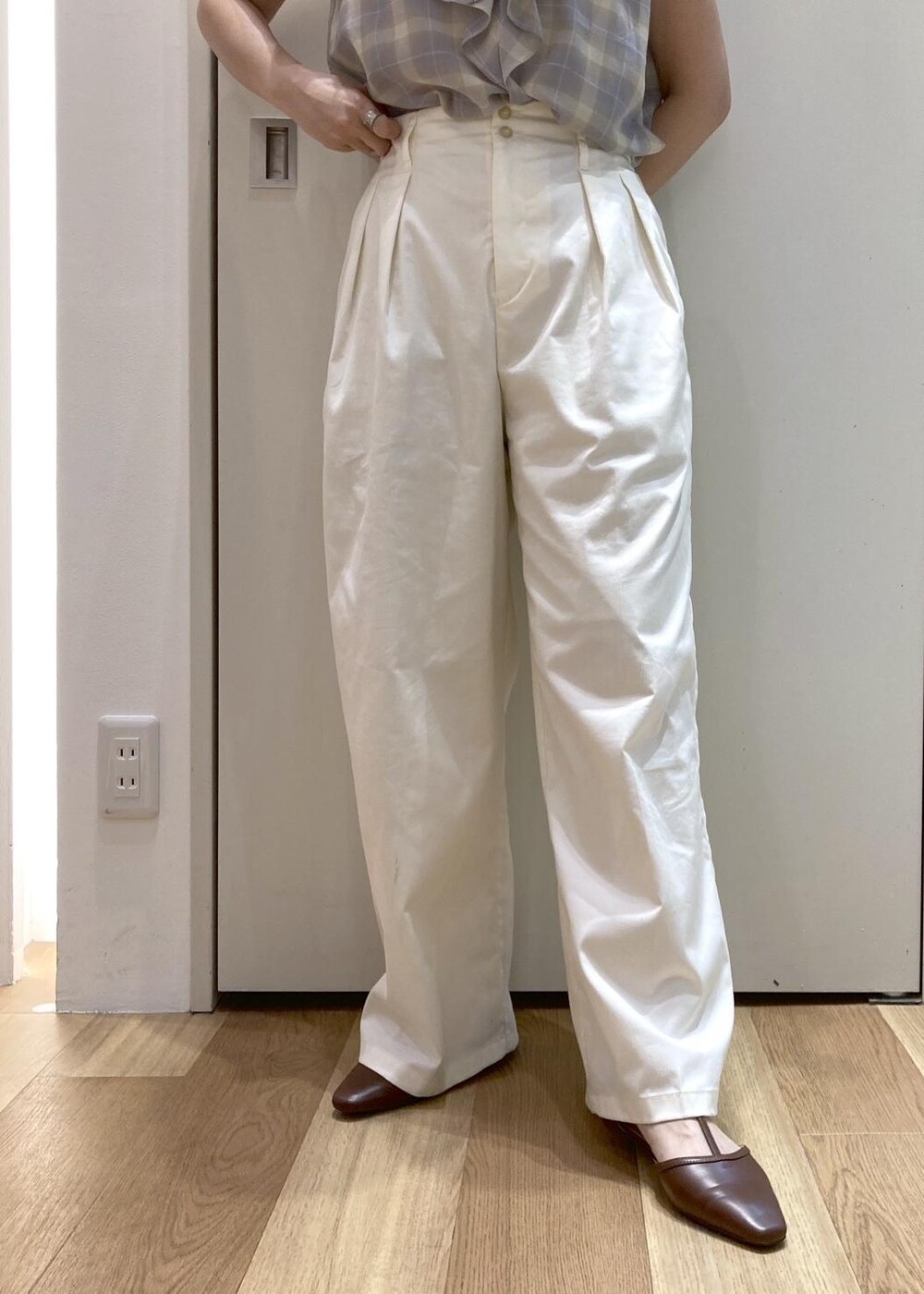ホワイト系のトートバッグ、ブラウン系のパンプス、ホワイト系のチノパンツを着用したレディースの夏コーディネートの4枚目の写真